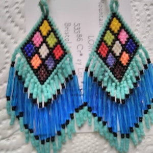 May include: A pair of turquoise and blue beaded earrings with a colorful square design in the center. The earrings are handmade and feature a fringe design.