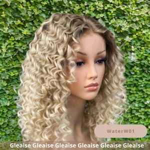 May include: A blonde curly wig with a light brown root. The wig is styled in a side part with loose curls. The wig is on a mannequin head against a green background. The text "WaterW01" is visible in the lower right corner of the image.