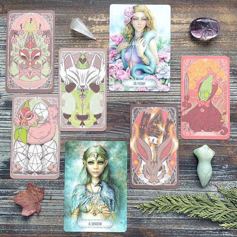 a collection of tarot cards, gemstones, and a leaf, arranged on a wooden surface.