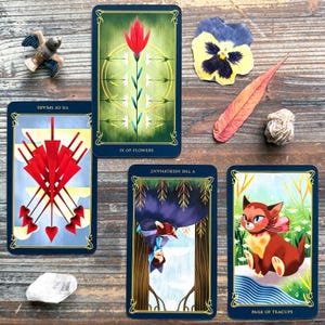 a collection of tarot cards, a crystal, and various natural elements such as a flower, leaf, and bird figurine, all arranged on a wooden surface.