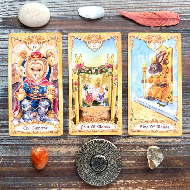 three tarot cards with illustrations of rabbits and a king, along with various crystals and stones arranged on a wooden surface.