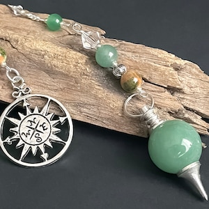 May include: A green aventurine pendulum with a silver compass charm and a silver chain with green and brown beads.