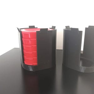 Peut inclure: Un ensemble de contenants empilables en plastique noir avec un insert en plastique rouge. Les contenants sont conçus pour contenir et organiser de petits objets.