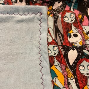 Peut inclure: Un tissu bleu clair avec une bordure cousue en zigzag violet est &agrave; c&ocirc;t&eacute; d'un tissu &agrave; motifs repr&eacute;sentant des personnages de L'&Eacute;trange No&euml;l de Monsieur Jack. Le tissu &agrave; motifs a un fond noir avec des images de Jack Skellington et Sally.