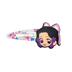 May include: A hair clip featuring a cartoon character's face with black hair, purple accents, and a pink bow. The clip is white with a floral pattern in pink, blue, and yellow. This accessory is suitable for various hairstyles.