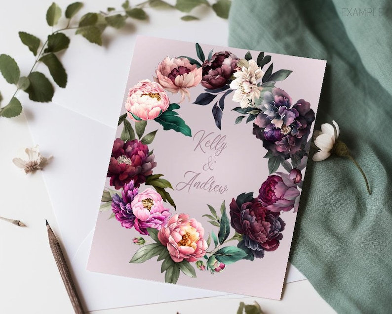 May include: A wedding invitation with a floral wreath design. The wreath is made of pink, purple, and green flowers. The text "Kelly & Andrew" is in the center of the wreath.