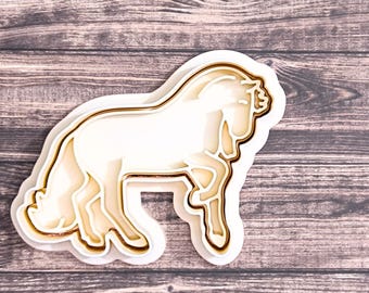 May include: A white plastic cookie cutter shaped like a horse. The cutter has a detailed outline of the horse's body and legs.