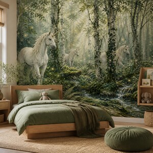 Könnte beinhalten: Ein Wandbild mit einer Waldszene, drei weißen Einhörnern, Birken, moosbewachsenen Felsen und einem kleinen Bach. Die Szene enthält leuchtende Lichtpartikel im Wald. Ein Holzbett mit olivgrüner Bettwäsche steht vor dem Wandbild.