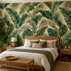 Pode incluir: Um quarto com uma parede coberta por papel de parede com um padrão de grandes folhas de palmeira tropicais verdes. A cama tem uma cabeceira clara, roupa de cama branca, uma manta verde e várias almofadas em tons de branco e verde-azeitona.