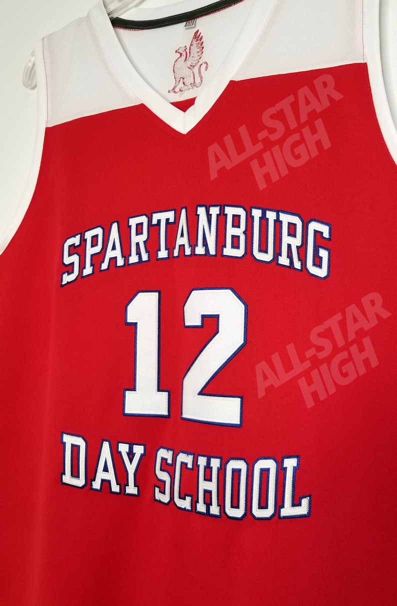 Op de afbeelding: Rood basketbaltenue met witte en blauwe letters. Het tenue staat "Spartanburg" "12" en "Day School" met de woorden "All-Star High" rechtsboven en rechtsonder op het tenue.