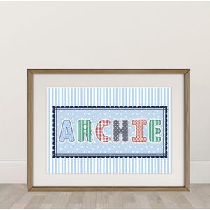 Può includere: Stampa incorniciata con il nome "ARCHIE" in lettere colorate e decorate. Le lettere sono poste su uno sfondo azzurro a pois, all'interno di un bordo smerlato blu navy. Lo sfondo presenta strisce blu verticali.