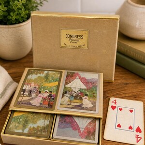 May include: A vintage Congress Playing Cards box with a gold-colored trim. The box is open, revealing four playing cards with landscape scenes. A single playing card with the number four and heart symbols is displayed.