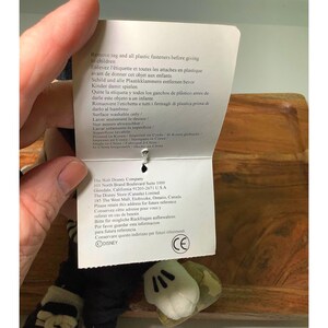 May include: A plush Mickey Mouse hand puppet with white gloves and a black and white striped sleeve. A tag with safety instructions and The Walt Disney Company information is attached.
