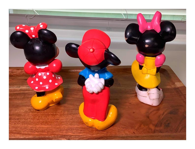 Pu&ograve; includere: Tre statuette vintage di Topolino e Minnie. La statuetta di Topolino indossa un berretto rosso, una camicia blu e pantaloni rossi. Le statuette di Minnie indossano abiti rossi a pois bianchi e abiti gialli con fiocchi rosa.