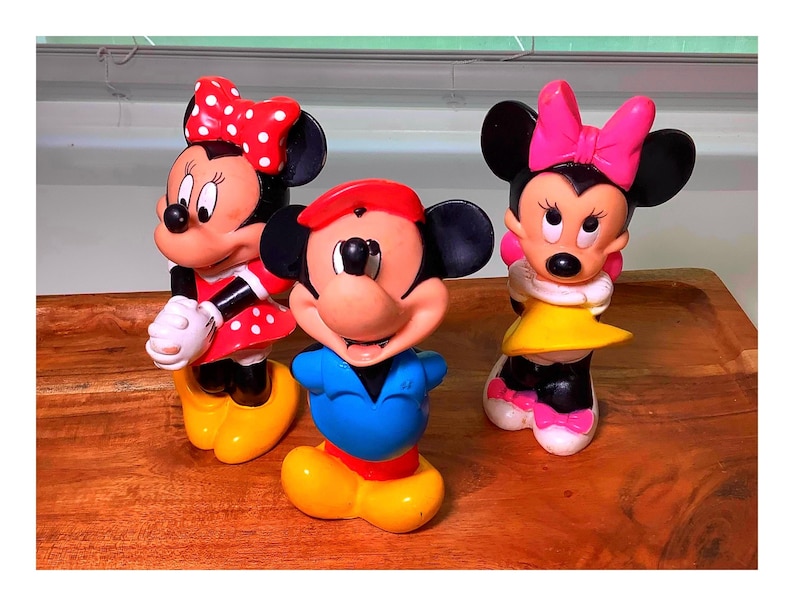 Pu&ograve; includere: Tre statuette vintage di Topolino e Minnie. Topolino indossa una camicia blu, pantaloncini rossi e un cappello rosso. Minnie indossa un vestito rosso a pois bianchi e un fiocco rosso. L'altra Minnie indossa un vestito giallo e un fiocco rosa.