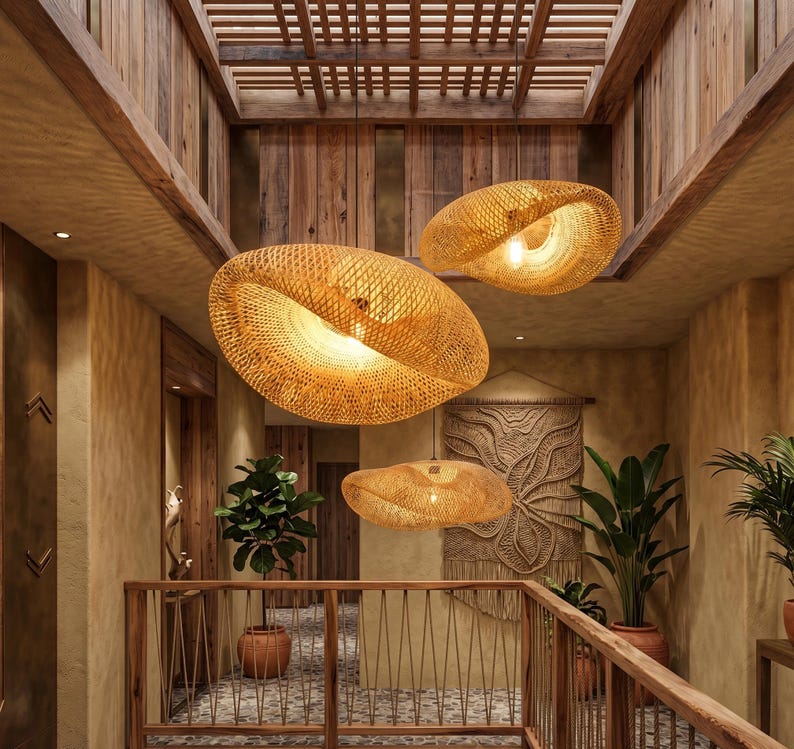 May include: Three woven rattan pendant lights hang in a hallway with wooden features. The lights are oval-shaped, with a warm, natural colour. The hallway includes plants, a macrame wall hanging, and a wooden railing, creating a natural, inviting atmosphere.