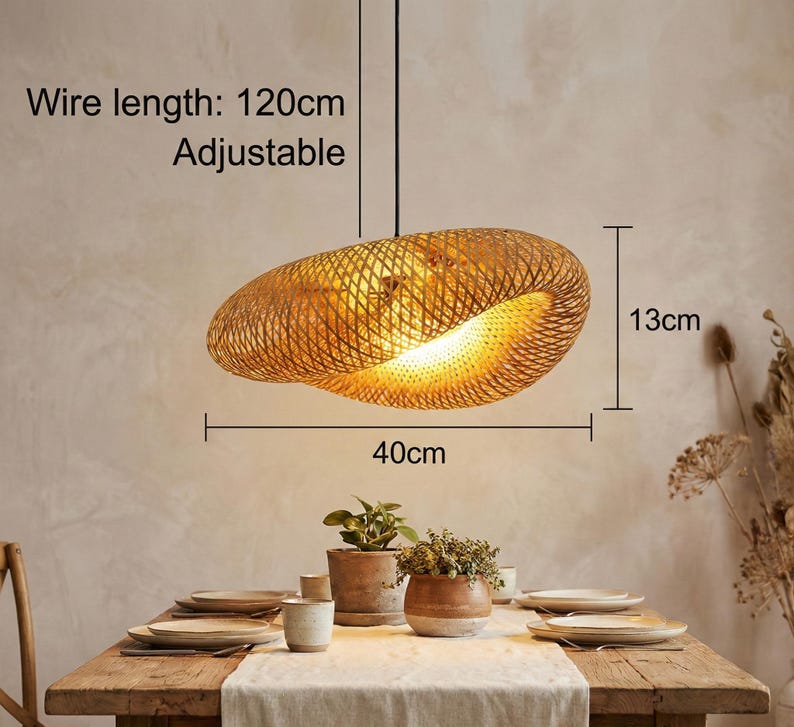 May include: A woven bamboo pendant light, 40cm wide and 13cm high, hangs above a dining table. The wire length is 120cm and adjustable. The light fixture has a warm, natural colour and casts a soft glow. The text on the image says "Wire length: 120cm Adjustable".