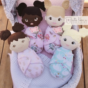 May include: Four handmade baby dolls in a white crocheted basket. The dolls are dressed in different outfits with floral and pineapple patterns. The dolls have different skin tones and hair colors.  "cute like u EMBROIDERY" is printed on a pink tag.