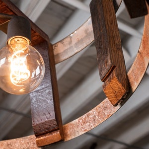 May include: A rustic wooden chandelier with a circular design and exposed light bulbs. The wood is dark brown with a natural finish and the metal is rusted.