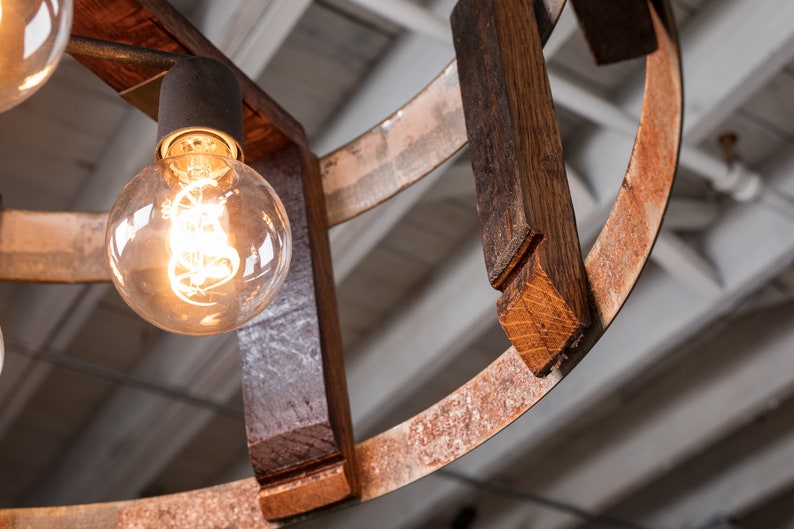 May include: A rustic wooden chandelier with a circular design and exposed light bulbs. The wood is dark brown with a natural finish and the metal is rusted.