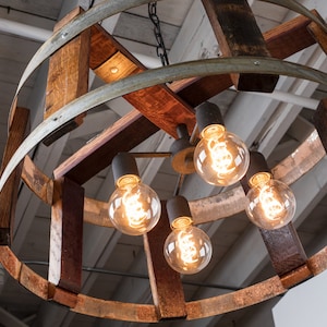 May include: A rustic chandelier made from repurposed wine barrels with five exposed light bulbs. The chandelier is made of wood and metal and has a natural, weathered finish.