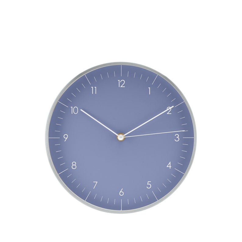 May include: A round, blue wall clock with white numbers and silver hands. The clock face is a light blue color and the hands are pointing to 12:00.