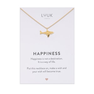 Könnte beinhalten: Goldkette mit einem Hai-Anhänger und einer Karte mit dem Text "Glück ist kein Ziel. Es ist eine Lebenseinstellung. Legen Sie diese Kette an, wünschen Sie sich etwas und Ihr Wunsch wird in Erfüllung gehen."