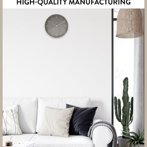 Op de afbeelding: Een witte bank met drie kussens, een grijze deken en een cactusplant in een pot. Boven de bank hangt een grijze klok met witte cijfers. De tekst "LUK LIFESTYLE HIGH-QUALITY MANUFACTURING" staat bovenaan de afbeelding.