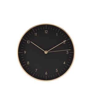 Può includere: Un orologio nero e dorato con numeri romani e lancette dorate.