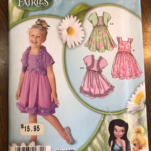 May include: A sewing pattern for a girl's dress with a ruffled bodice and skirt. The pattern includes three different styles: a pink dress with a ruffled bodice, a green dress with a ruffled bodice and a matching jacket, and a pink dress with a ruffled bodice and a matching sash. The pattern is from Simplicity and is for sizes 3-8.