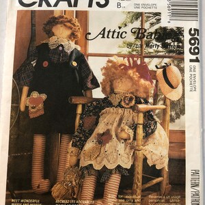 May include: A sewing pattern for two rag dolls named Maisie and Mortie Huckabee. The pattern includes instructions for making the dolls, which are 27 inches tall, and their clothes. The pattern cover features a colorful illustration of the dolls.