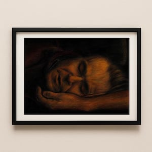 Può includere: Un'opera d'arte incorniciata con un ritratto di una persona che dorme. L'opera è realizzata in toni caldi e terrosi, con il volto e la mano in primo piano. La cornice nera contrasta con il muro di colore chiaro.