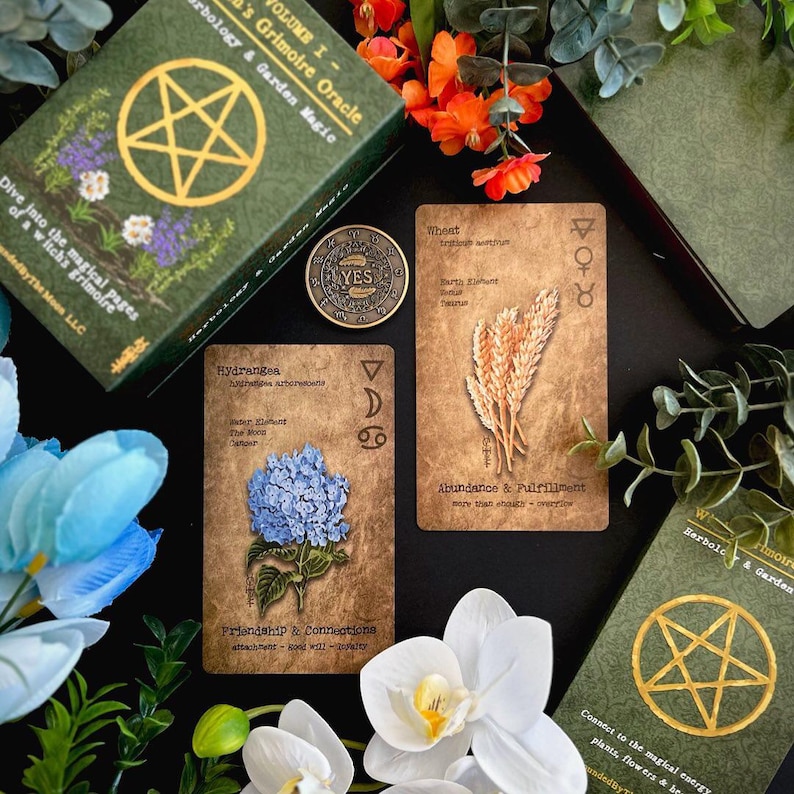 May include: An oracle deck with a green box featuring a gold pentagram and the text "Herbology & Garden Magic". The deck includes cards with botanical illustrations and text, a coin with "YES" on it, and decorative flowers.