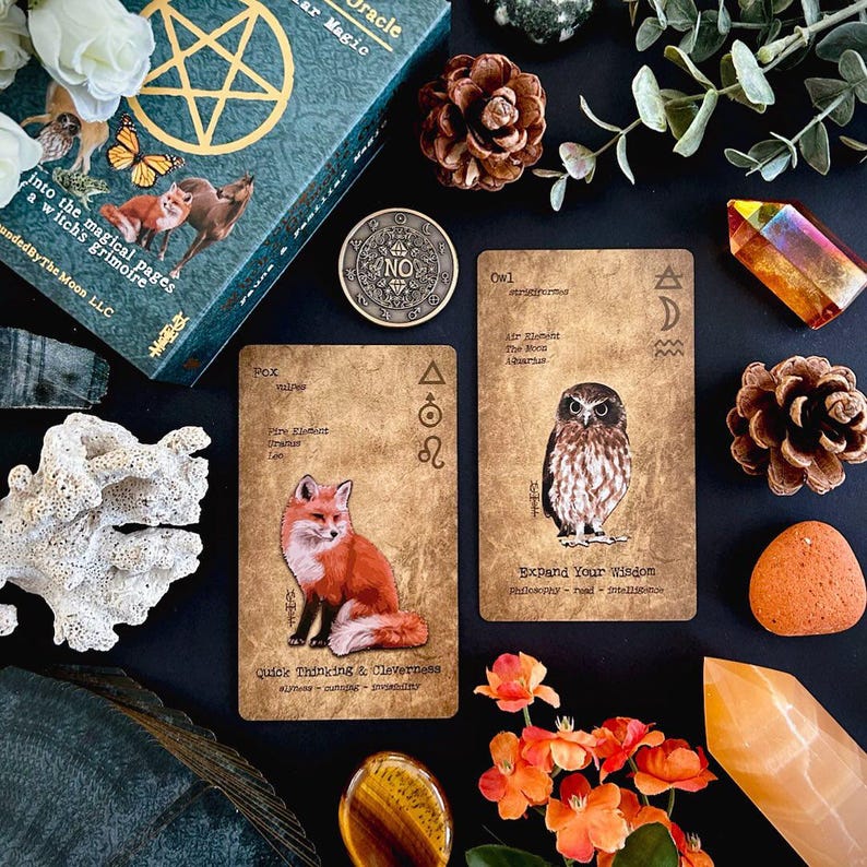 May include: An oracle card deck with a teal box featuring a pentagram design and the text "Star Magic". Two oracle cards show a fox and an owl. Other items include crystals, flowers, and a coin.