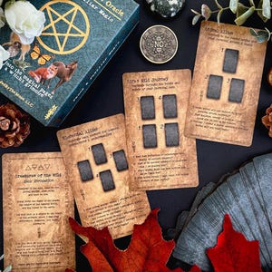 May include: A teal and gold oracle card deck with the title "Fauna Familiar Magic Oracle" and the text "into the magical pages a witch's grimoire". Several oracle cards are displayed, along with a coin and decorative elements.