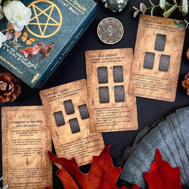 May include: A teal and gold oracle card deck with the title "Fauna Familiar Magic Oracle" and the text "into the magical pages a witch's grimoire". Several oracle cards are displayed, along with a coin and decorative elements.