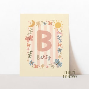 Puede incluir: Una impresión artística caprichosa con una gran letra "B" rosa sobre un fondo a rayas. El nombre "Betsy" está escrito debajo de la letra. La impresión está decorada con mariposas, flores, un sol, una luna y estrellas, todo en colores pastel suaves.