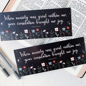 Op de afbeelding: Twee zwarte bladwijzers met witte bloemenpatronen en witte tekst. De tekst luidt "Toen de angst groot was in mij, bracht uw troost mij vreugde." en "PSALM 94:19".