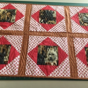 May include: A brown and white quilt with a red and white checked pattern. The quilt features six diamond-shaped panels, each with a different image of a dog.