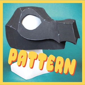 May include: A black paper dragon head pattern, with eye and snout details, sits on a white form. The word "PATTERN" is displayed in yellow with a red outline. The background is teal with a yellow border.