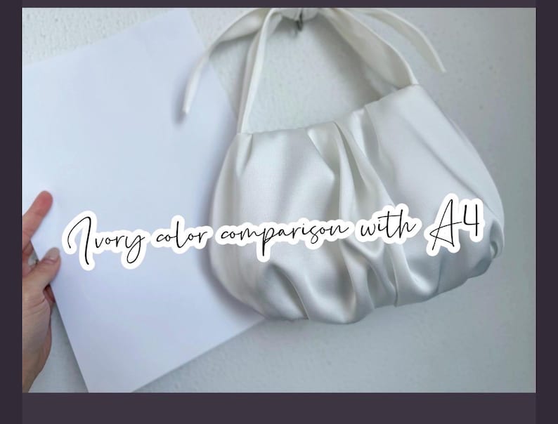 May include: An ivory-colored, gathered satin handbag with a knotted handle, positioned next to a standard A4 sheet of white paper. The text "Ivory color comparison with A4" is overlaid on the image in a white script font.