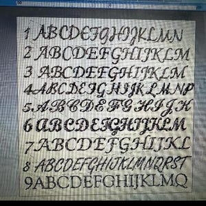 May include: A digital display showing nine distinct rows of black cursive alphabet letters, each numbered one through nine. The letters are presented in various calligraphic styles against a light, grid-patterned background with a ruler visible at the top.