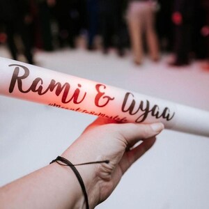 May include: White foam tube with the text "Rami & Liyaa" in black script. The tube is lit from inside with a red glow.