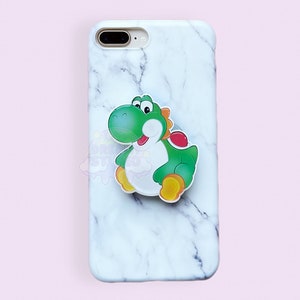 May include: A white marble iPhone case with a green Yoshi character pop socket.