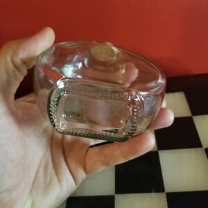 May include: A clear glass bottle with a textured bottom. The bottle is empty and has a cork stopper.