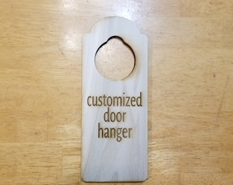 May include: A wooden door hanger with a round cutout and the text "customized door hanger" engraved on it.