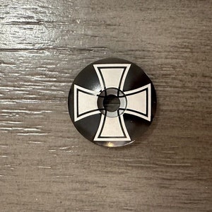 May include: Black and white bicycle headset cap with a stylized iron cross design.