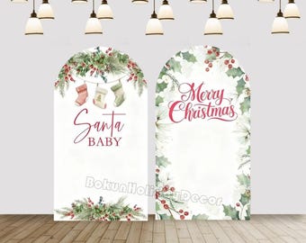 May include: Two white arched Christmas backdrops. One features the text "Santa Baby" with hanging stockings and festive greenery. The other has the text "Merry Christmas" with holly and berries.