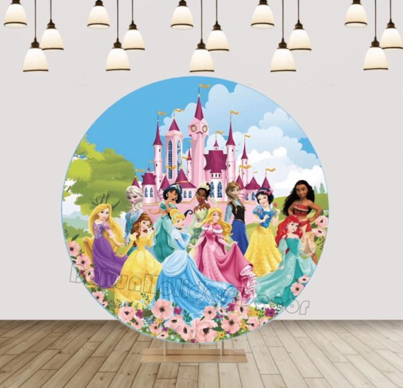 May include: A round backdrop features Disney Princesses in front of a pink castle.  The princesses are depicted in their signature gowns, including Cinderella, Belle, Jasmine, Tiana, Rapunzel, and more. The backdrop is predominantly light blue and pink, with green foliage and flowers at the base. It's perfect for birthday parties or princess-themed events. The high-quality print ensures vibrant colors and sharp details. This round backdrop is approximately 60 inches in diameter and is made of durable, wrinkle-resistant fabric.