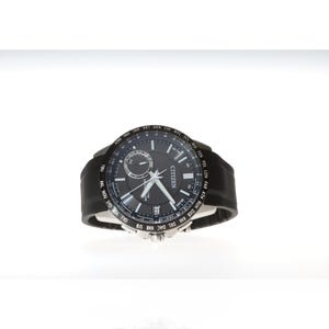 Op de afbeelding: Citizen-horloge met een zwarte wijzerplaat en een zwarte leren band. De wijzerplaat heeft zilveren wijzers en markeringen, met het Citizen-logo en tijdzone-aanduidingen rond de bezel.